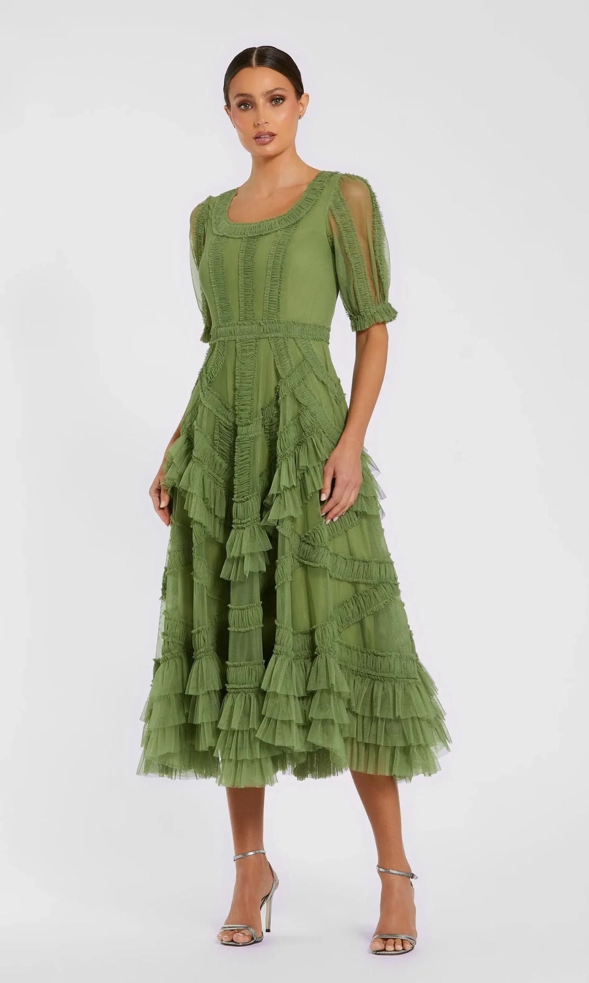 A woman models the Mac Duggal 8248 Midi Wedding Guest Dress, featuring ruffles, sheer sleeves, and a layered midi skirt, paired with silver open-toe heels against a plain background.